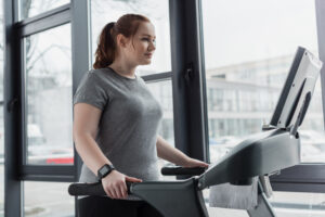Obese girl walking on treadmill in gym